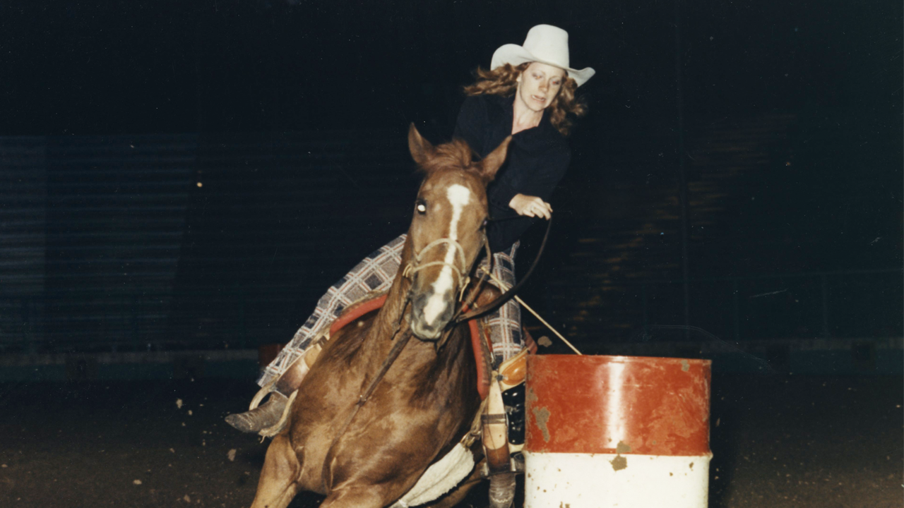 Reba rides horse around barrel 